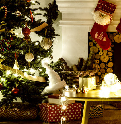 Cozy Christmas living room with decorated tree, stockings, and fireplace.
